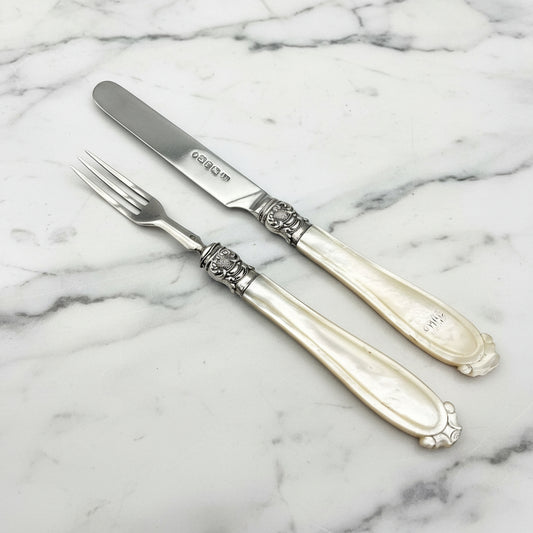 Antique silver knife and fork set with ornate collars and mother of pearl handles.