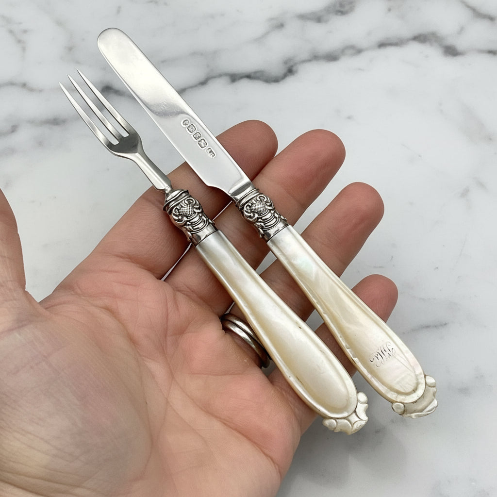 antique silver cutlery held in a hand over a marble surface