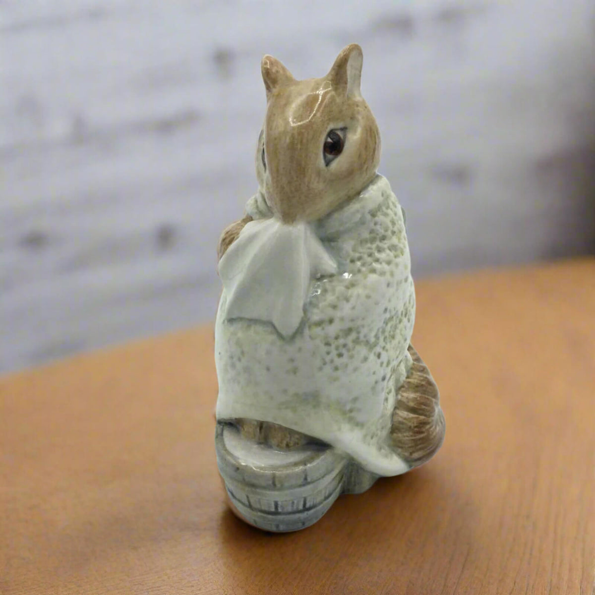 chippy hackee figurine holding a white cloth on a wooden surface with a blurred background