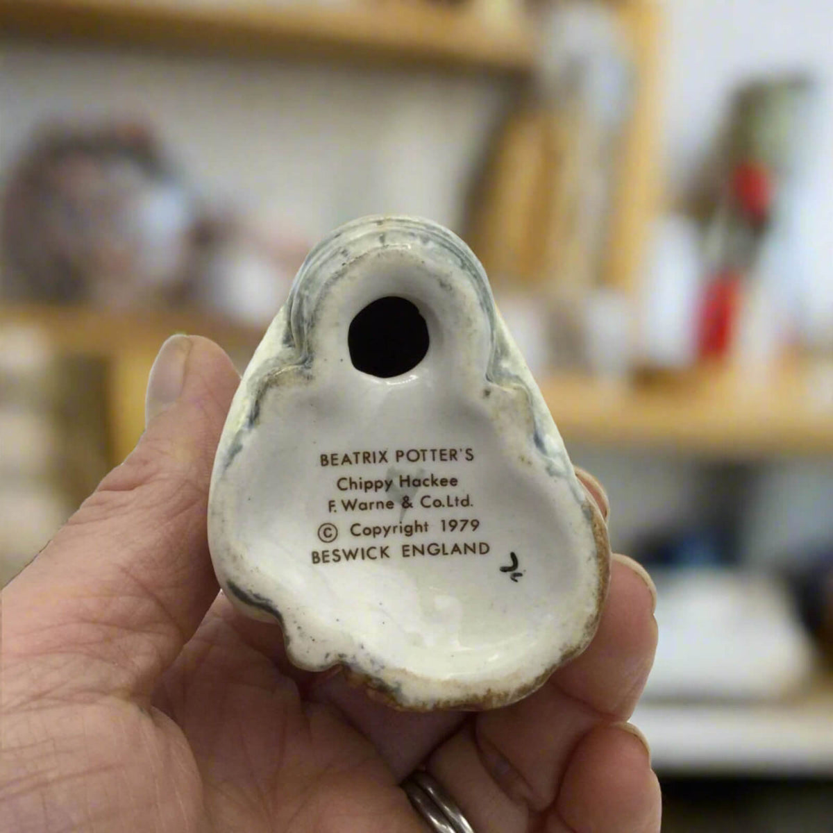 Hand holding a ceramic item with 'Beatrix Potter' branding and text.