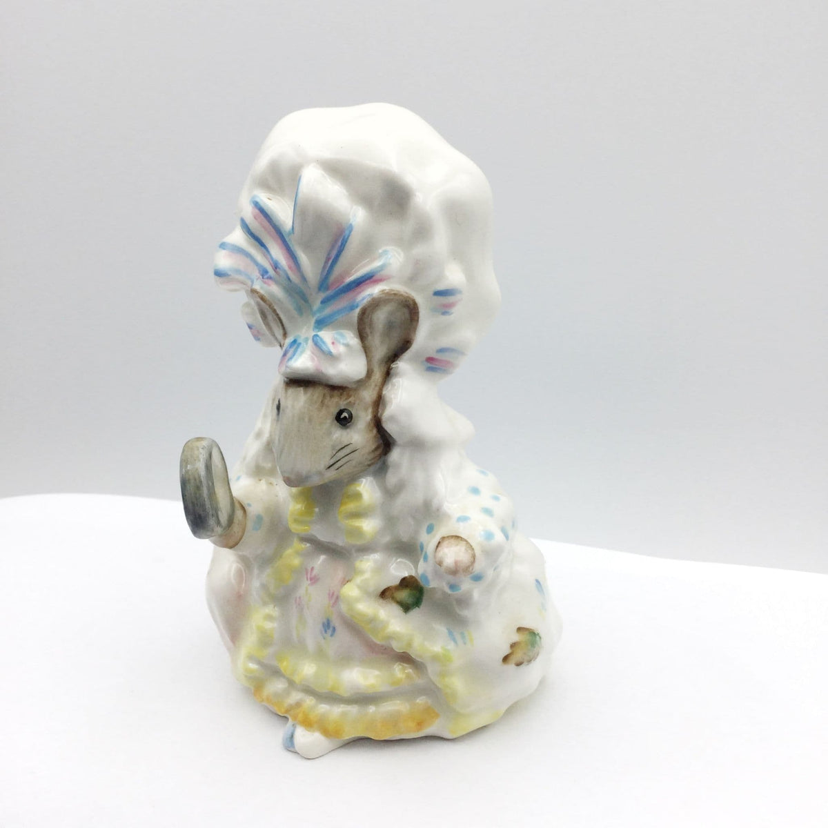lady mouse figurine on a white coloured shelf and grey wall behind