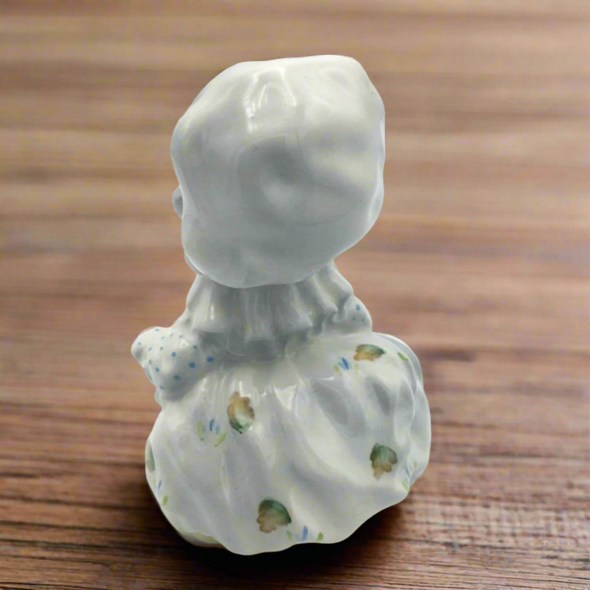 Ceramic figurine of a mouse in a dress on a wooden surface