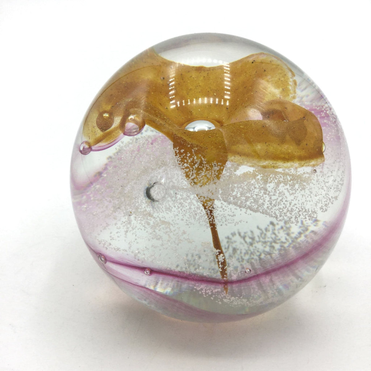 Caithness glass paperweight with an orange flower and pink swirls on a white background