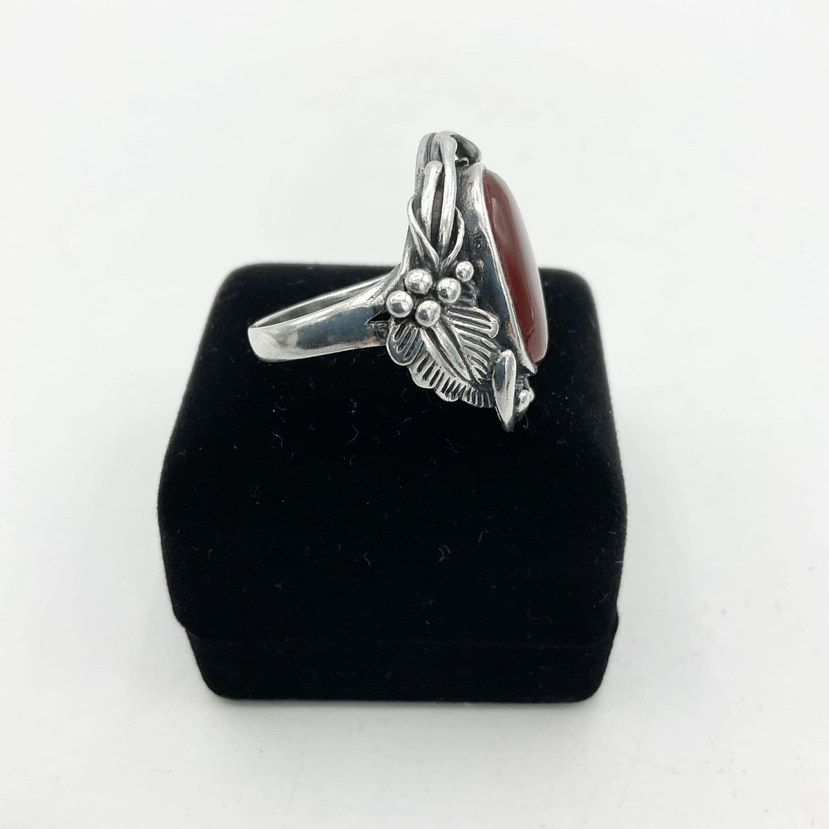 Silver grapes and leaves on side of silver ring on black box