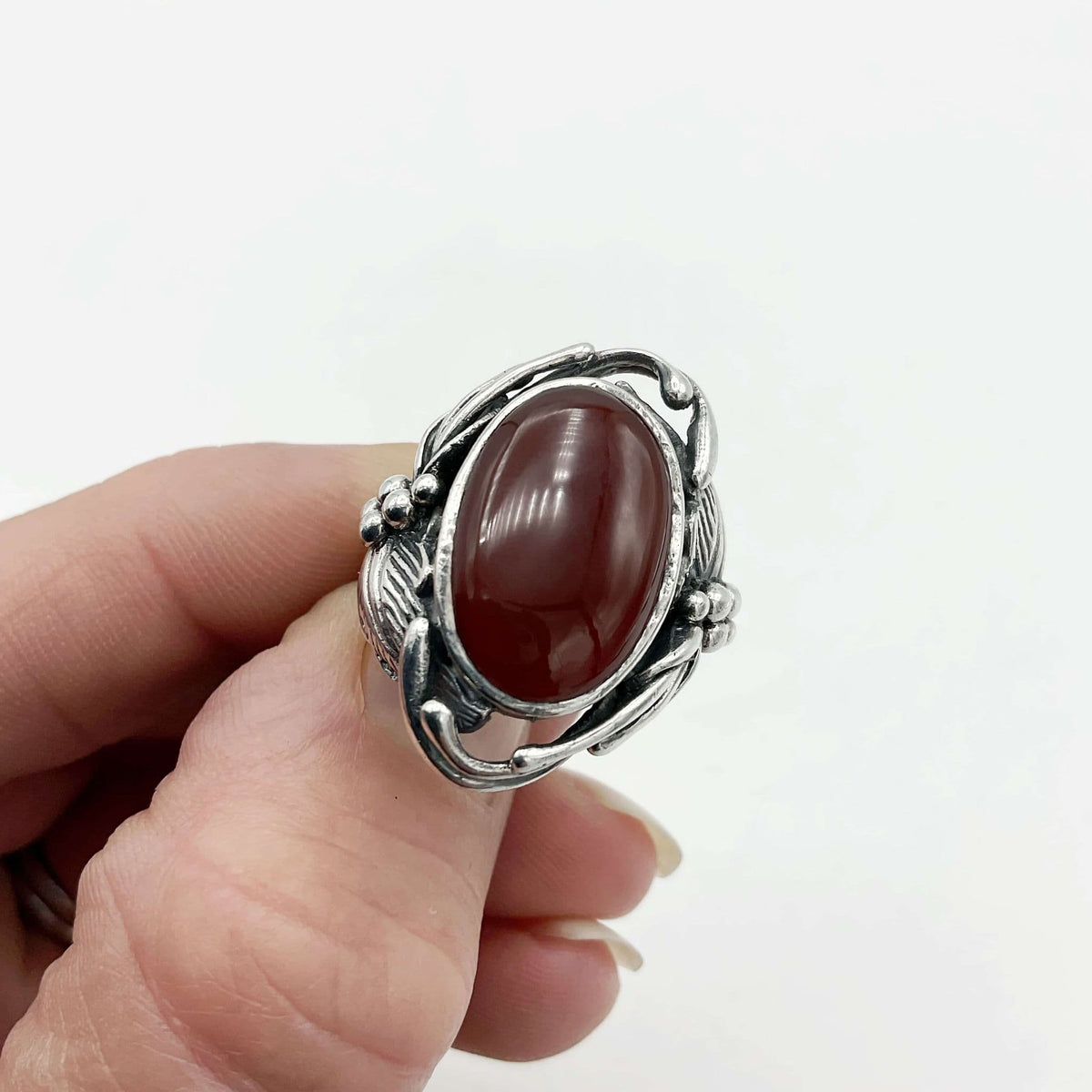Beautiful orange Carnelian gemstone silver ring held in fingers