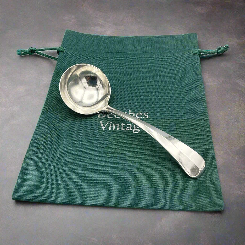 Silver ladle on a Beeches Vintage green gift bag and a granite background