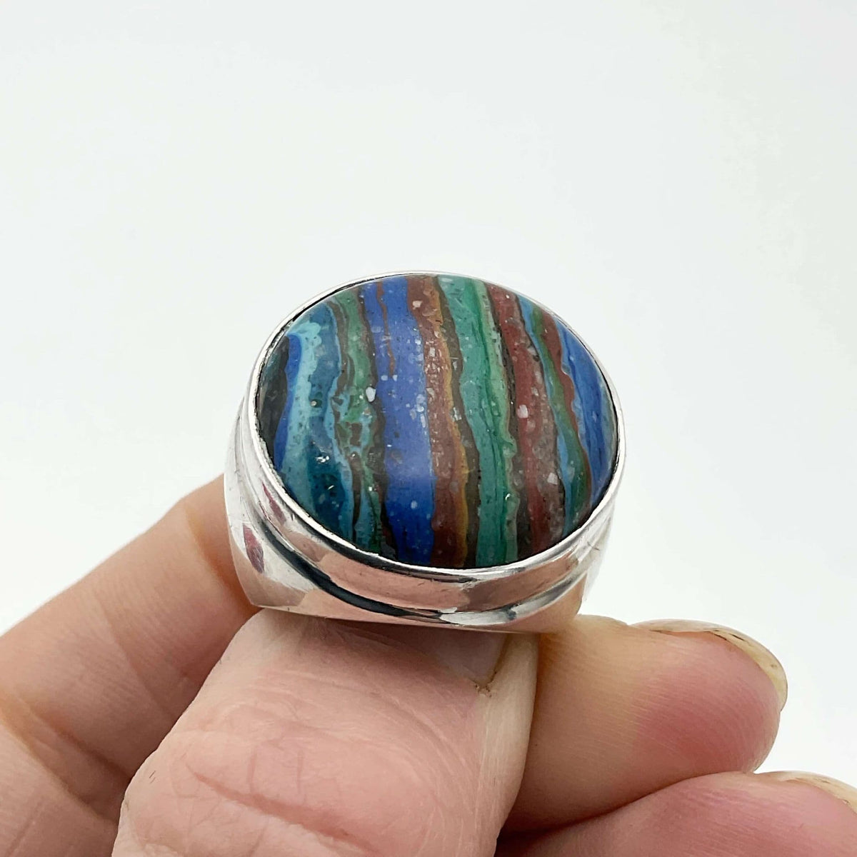 Multicoloured Rainbow Calsilica silver ring with vibrant gemstone in a detailed silver band, displayed on a neutral background.