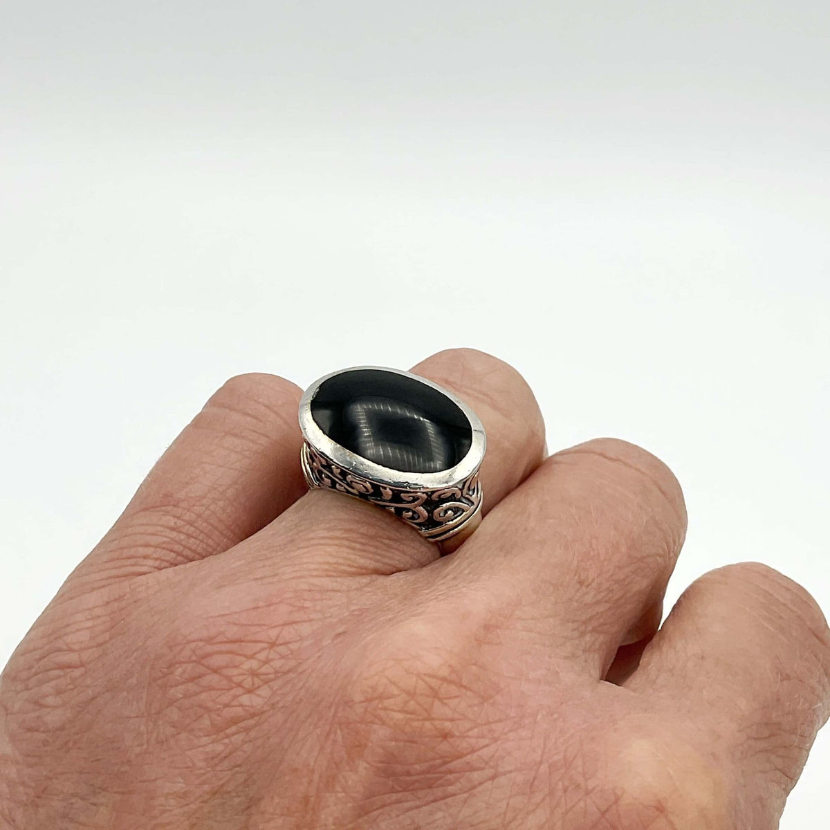 Oval black onyx silver ring with intricate band design from Beeches Vintage, showcasing a polished black onyx stone in a silver setting.