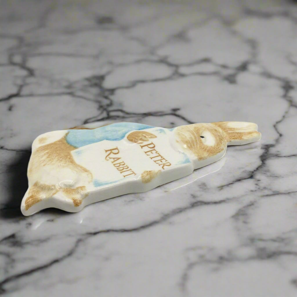 Side view of Peter Rabbit plaque on a marble surface
