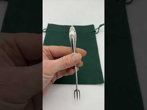 Video short of Antique silver plated pickle fork with an ornate handle held in a hand