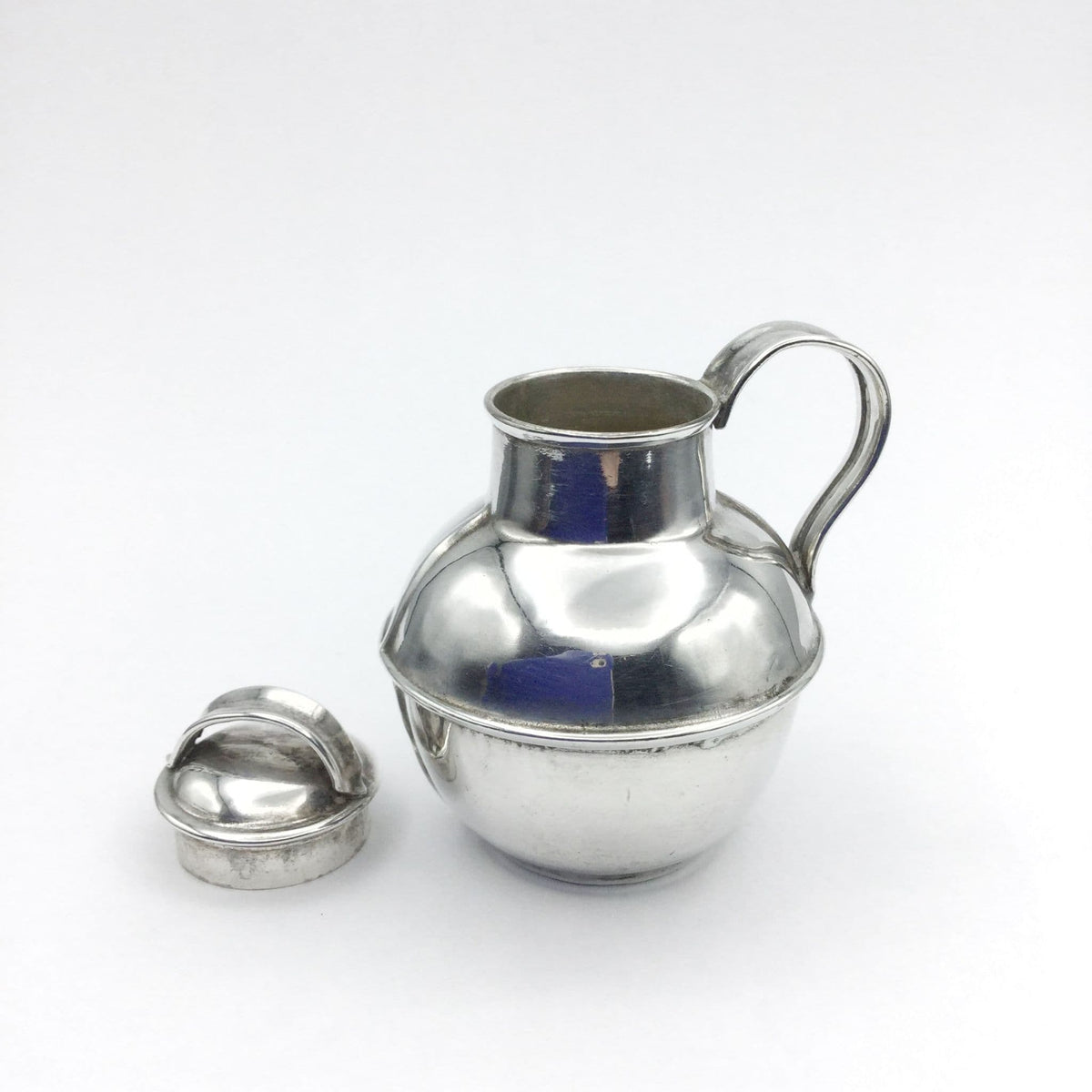 silver plated jug urn with the lid off on a plain background