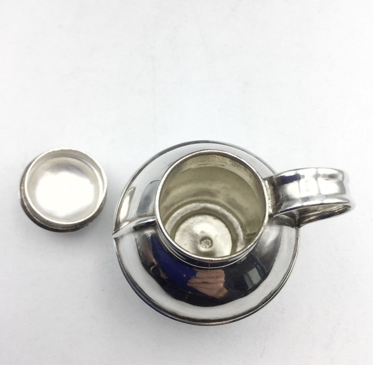 inside of silver plated jug urn on a plain background