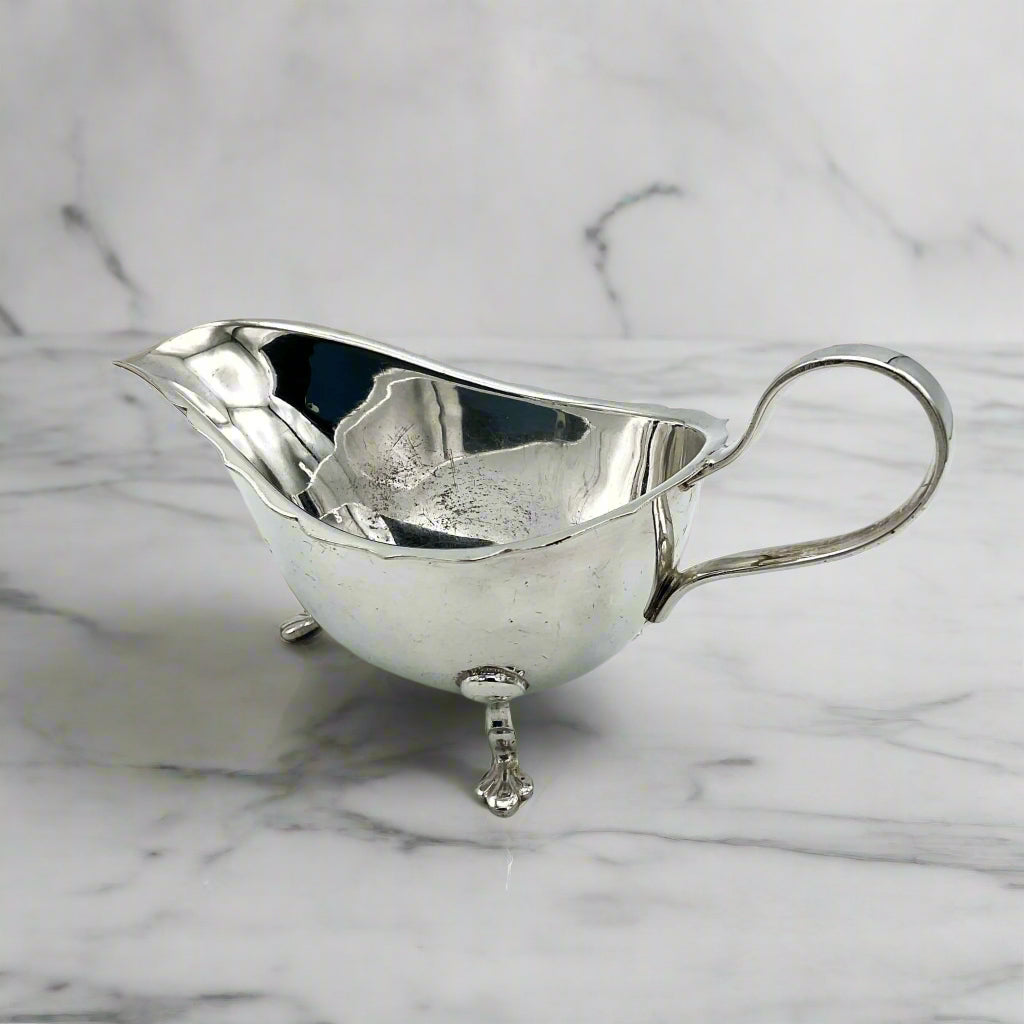 back of silver plated gravy boat on a marble surface
