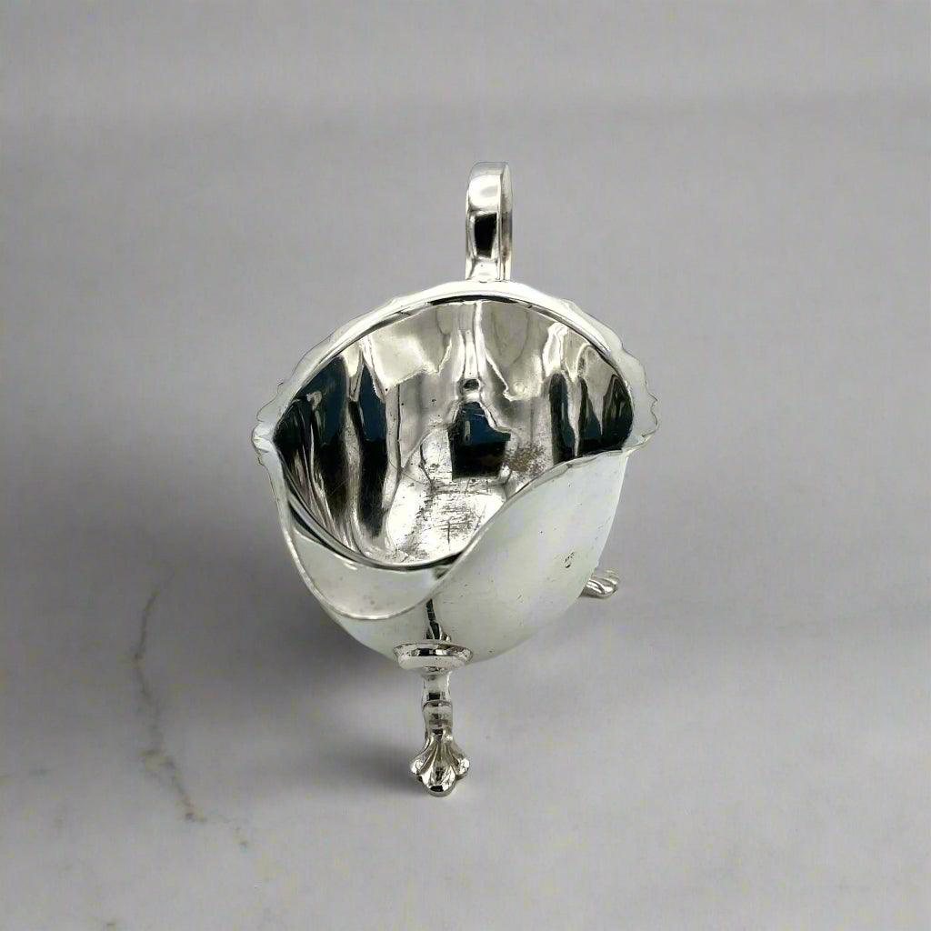 front of silver plated gravy boat on a light marble surface