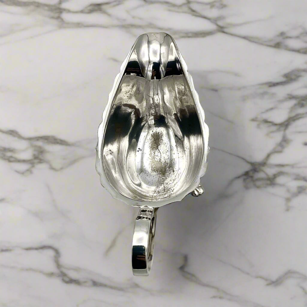 silver plated gravy boat inside on a marble worktop
