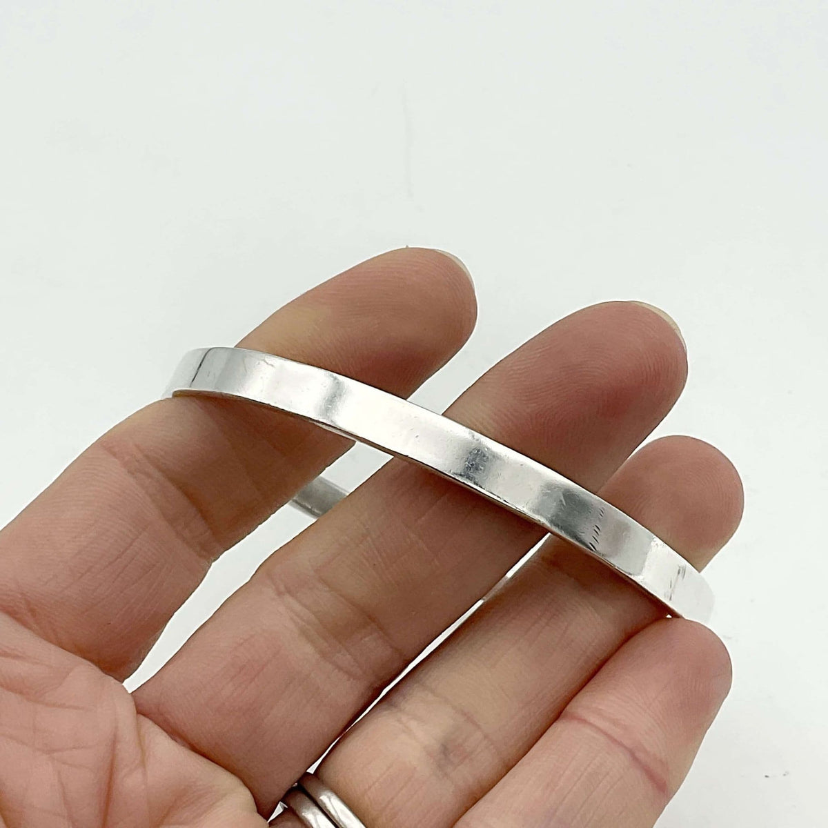 Sterling silver bangle bracelet by Beeches Vintage, showcasing a smooth, polished circular design on a neutral background.