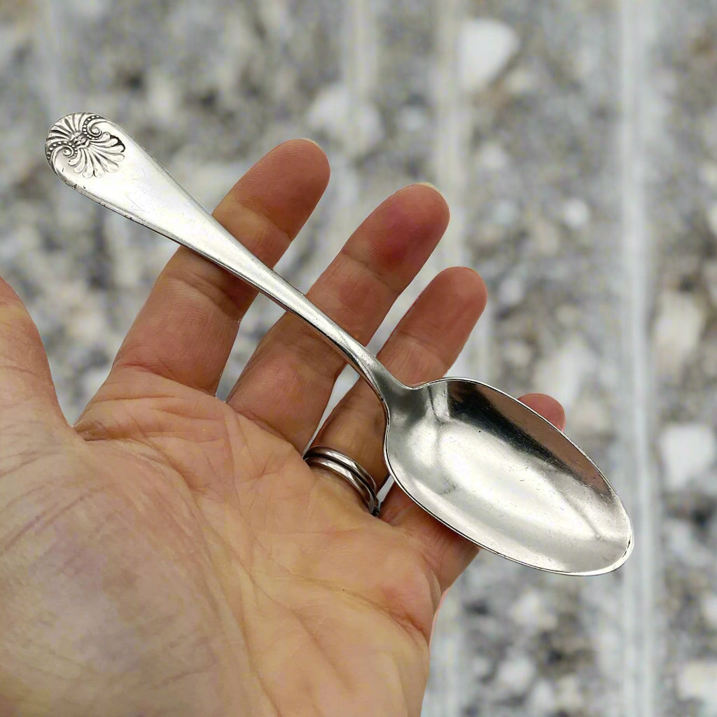 silver plated spoon held in a hand with a marble background