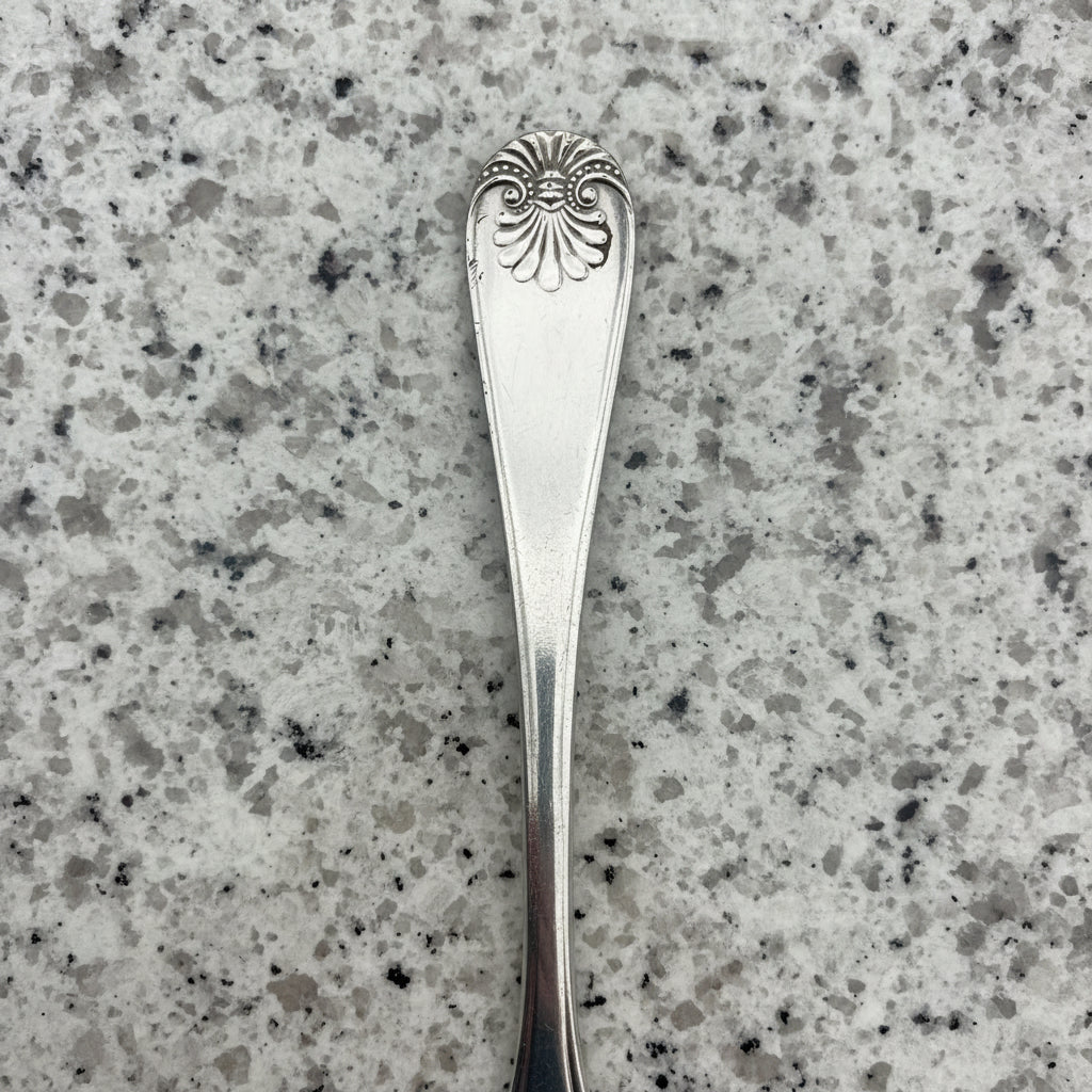 silver plated handle of spoon on a granite surface