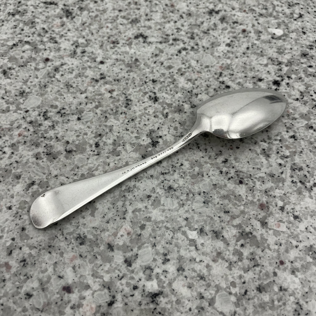 back of silver plated spoon on a dark granite surface