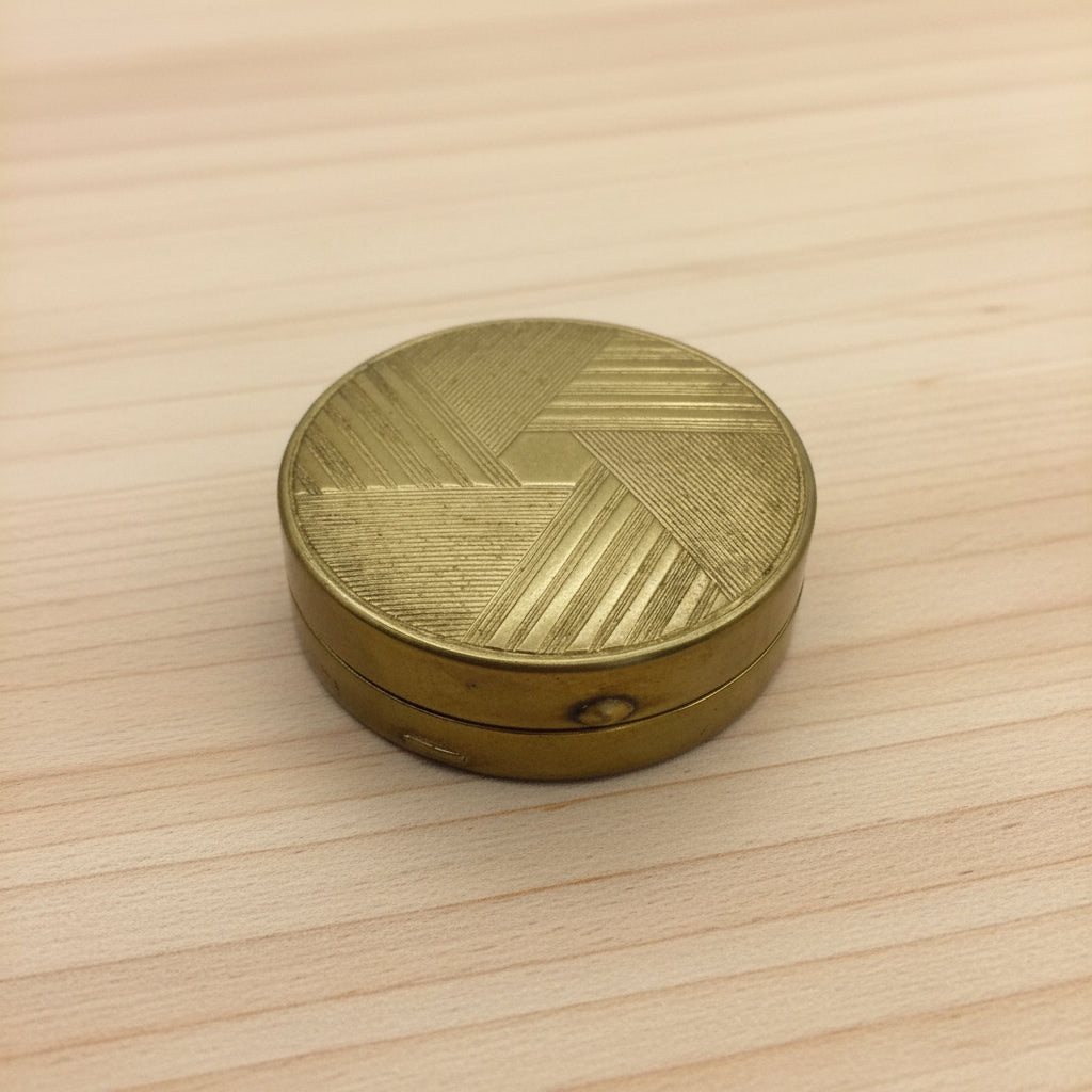 beautful patterned brass compact mirror on a wood table