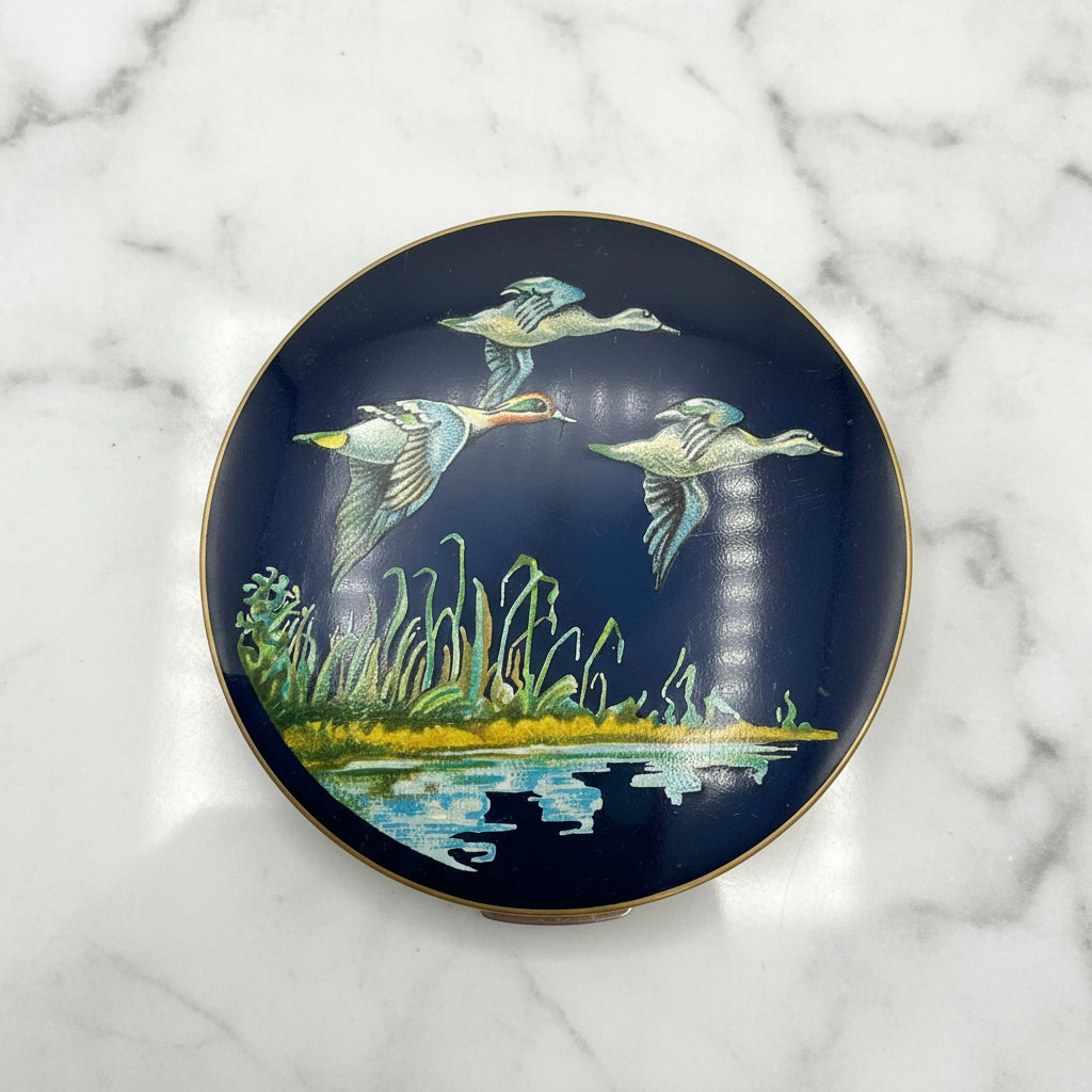 beautiful enamel featuring three ducks flying over water on a mirror compact lid and marble background
