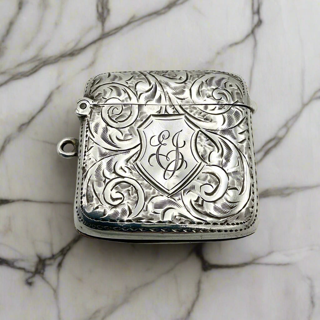 Antique sterling silver Vesta case with art nouveau design and a shield with EJ engraved in the centre, featuring a loop on one side.
