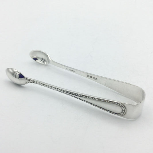 silver plated sugar tongson a white background with a dash pattern on it's arm and EPNS on the inside