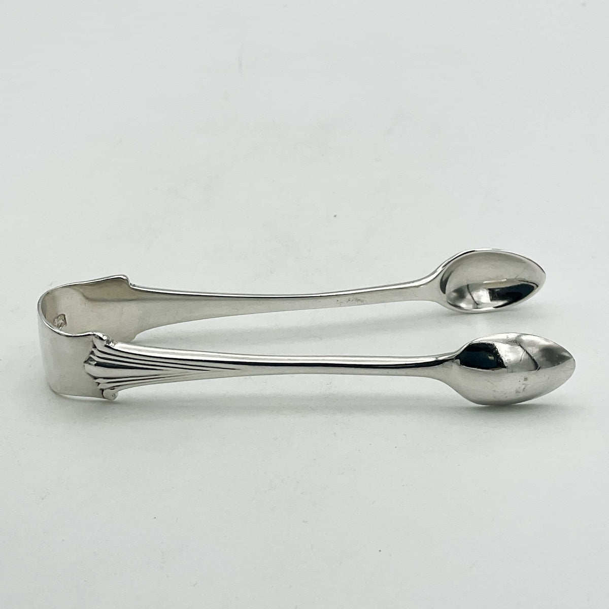 Silver sugar tongs showing an art deco design to the art on a white background