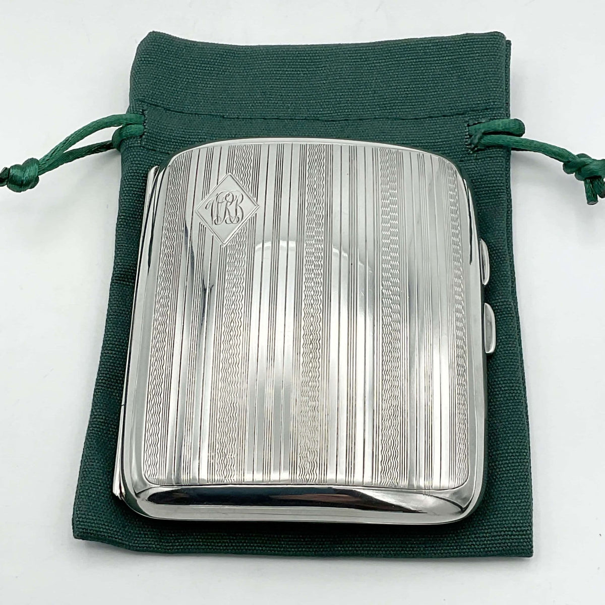 Antique 1920s silver cigarette case on a green cotton bag