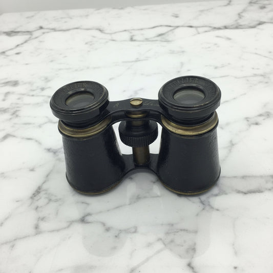 Black binoculars with brass accents on a marble surface