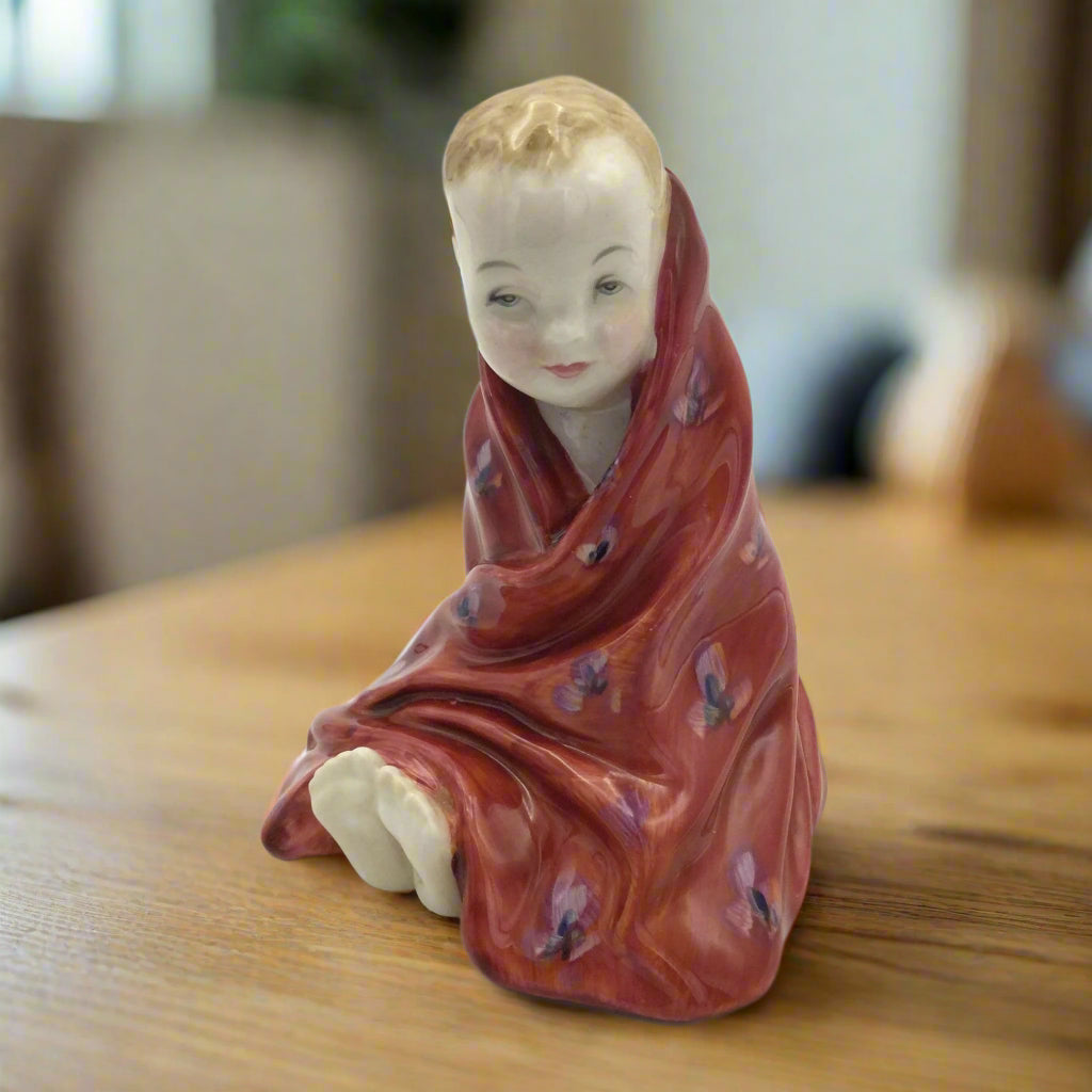 Royal Doulton figurine of a boy wrapped in a red patterned towel on a wood table